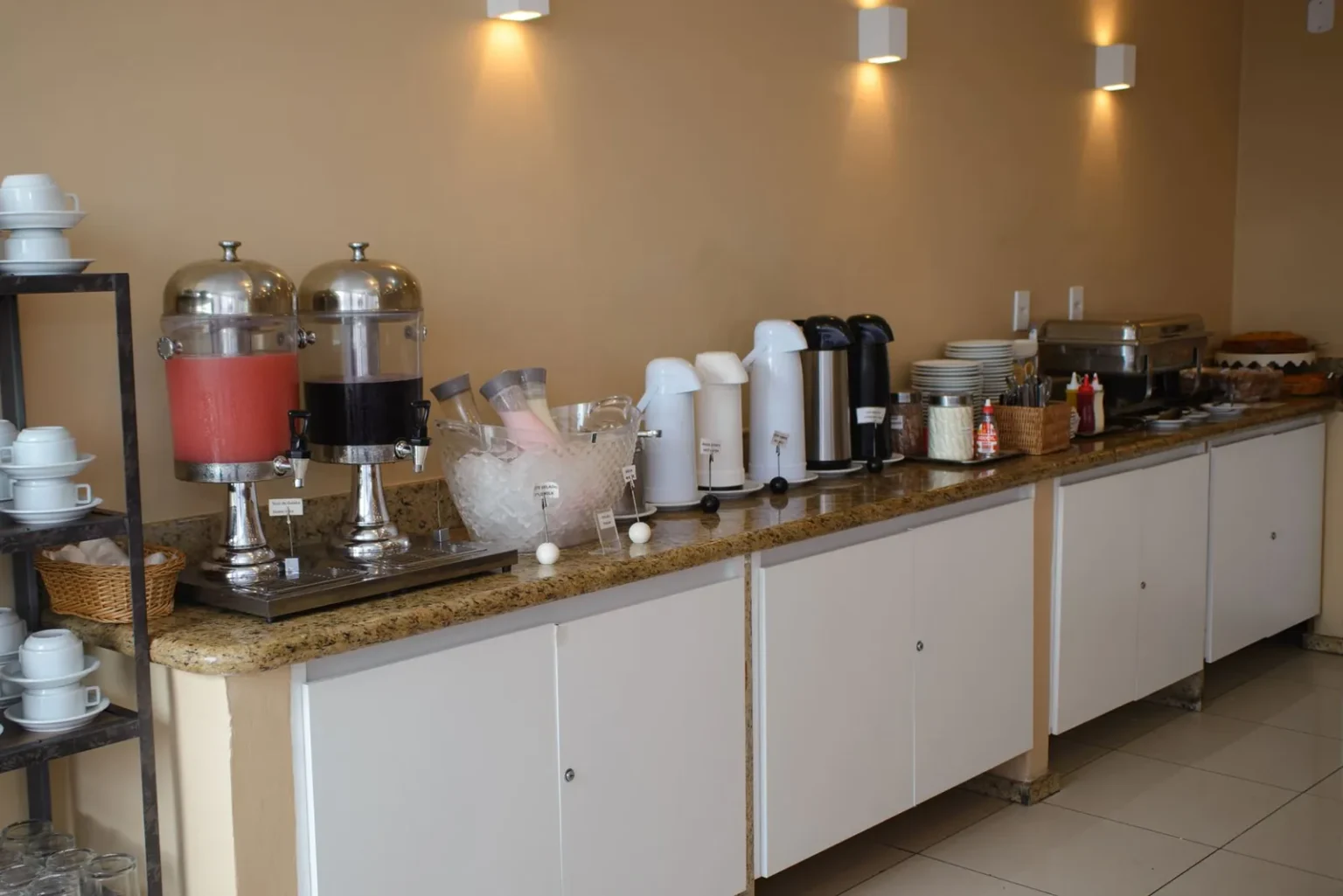 Bancada do café da manhã do Hotel Cantareira com sucos, térmicas, frios e bolos