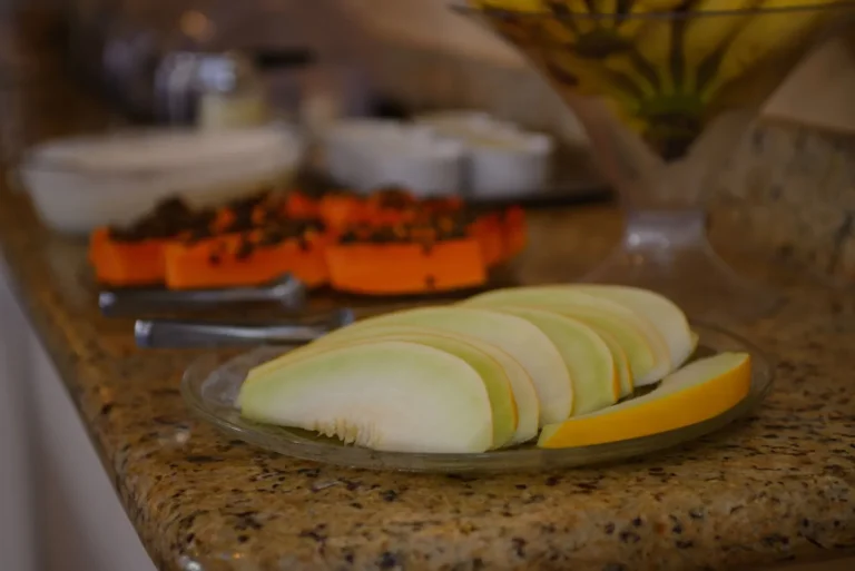 Melão e mamão fatiados no bufê de frutas