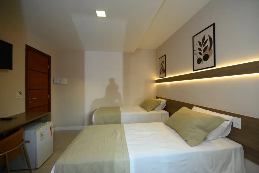 Quarto Standard Duplo com duas camas de solteiro, cabeceira com luz indireta e quadros botânicos